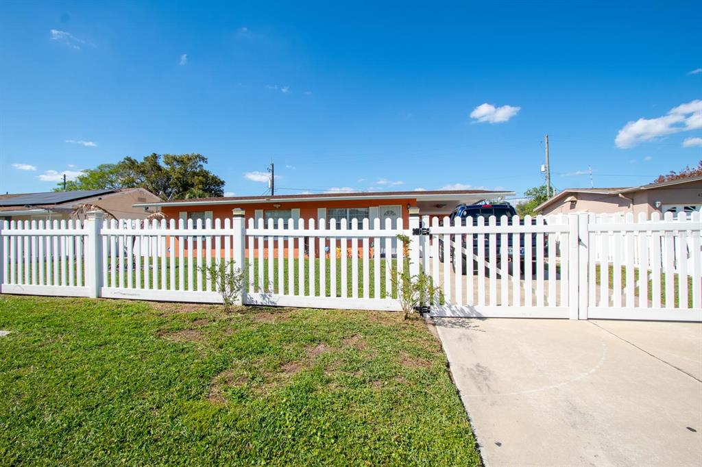 A white picket fence encloses the front yard of an orange house with a driveway — 4401 EDGEBROOK, ORLANDO, FL
