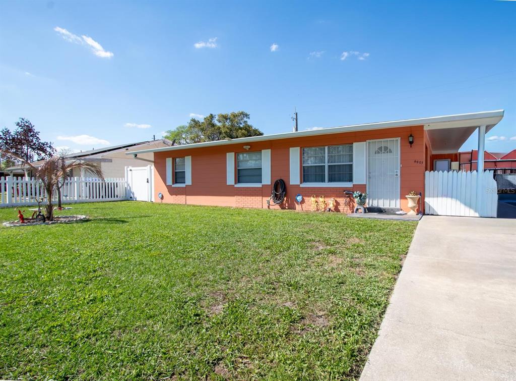 A single-story orange house with a white fence, a driveway, and a front lawn — 4401 EDGEBROOK, ORLANDO, FL