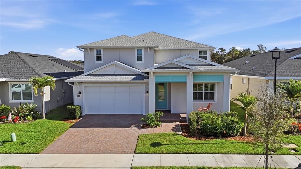 A two-story suburban house features a light-colored exterior, a brick driveway, and a turquoise door — 3610 ARBORDALE LOOP, SANFORD, FL
