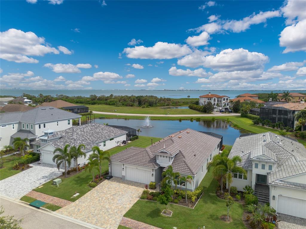 An aerial view shows several suburban houses with tiled roofs near a small pond — 5504 TITLE ROW DRIVE, BRADENTON, FL