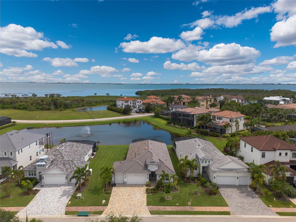 An aerial view of suburban houses with tile roofs situated near a pond and bay — 5504 TITLE ROW DRIVE, BRADENTON, FL