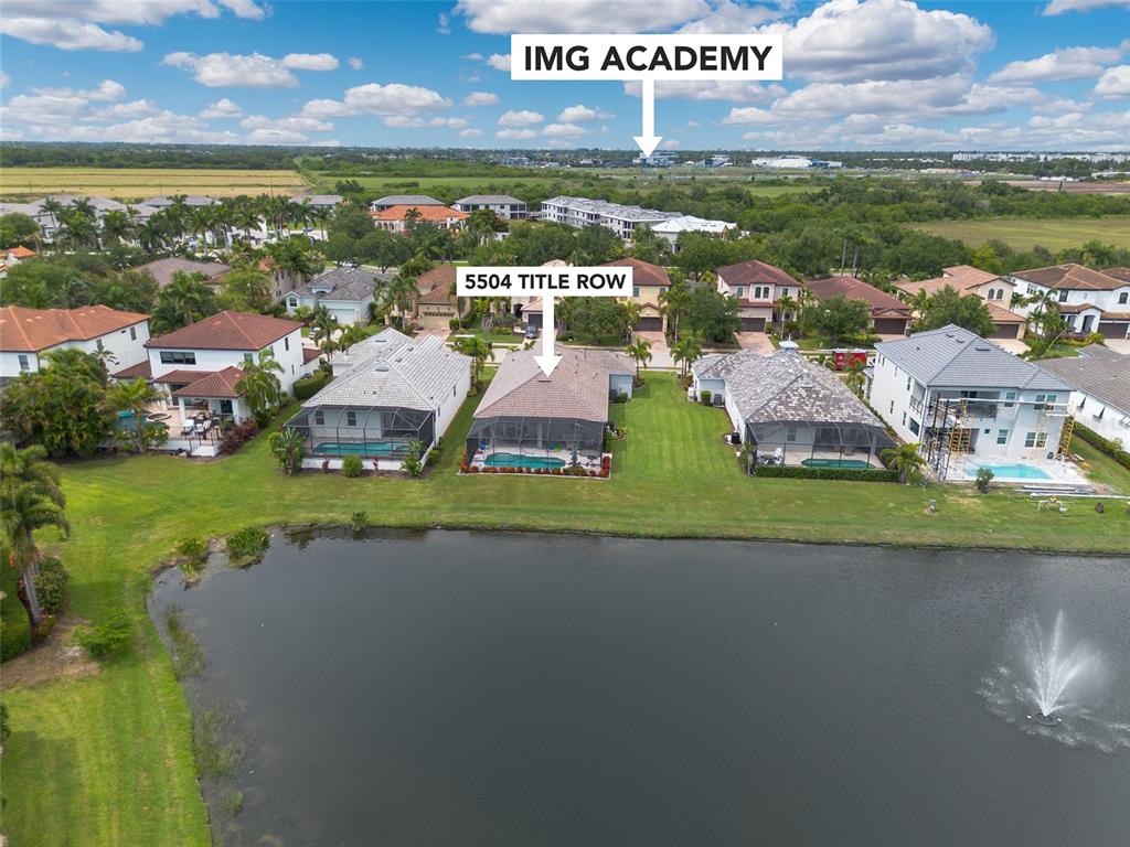 An aerial view shows a residential neighborhood with houses bordering a lake and a fountain — 5504 TITLE ROW DRIVE, BRADENTON, FL