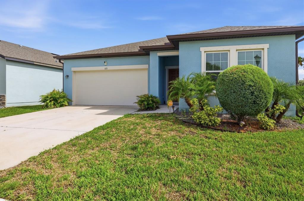 A light blue single-story house features a two-car garage and a manicured front lawn — 1121 ANCHOR BEND DRIVE, RUSKIN, FL