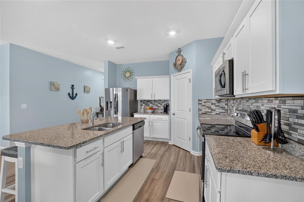 A kitchen features white cabinets, granite countertops, stainless steel appliances, and light blue walls — 1325 ANCHOR BEND DRIVE, RUSKIN, FL