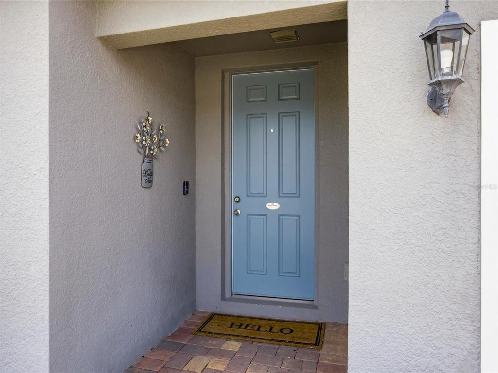 A blue front door with a welcome mat sits in a recessed entryway — 125 ANDREAS STREET, WINTER HAVEN, FL