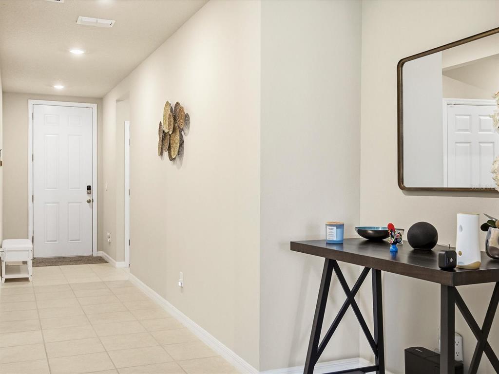 A bright entryway features a white front door, tile flooring, and a dark console table — 125 ANDREAS STREET, WINTER HAVEN, FL