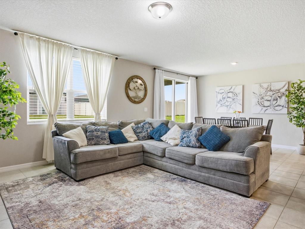 A living room features a large gray sectional sofa, a patterned rug, and tile flooring — 125 ANDREAS STREET, WINTER HAVEN, FL