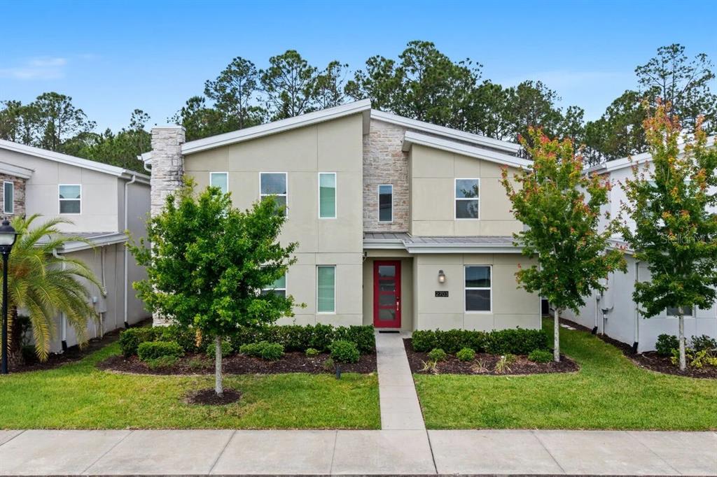 A two-story modern house features a red front door, stone accents, and a concrete walkway — 2703 BOOKMARK DRIVE, KISSIMMEE, FL