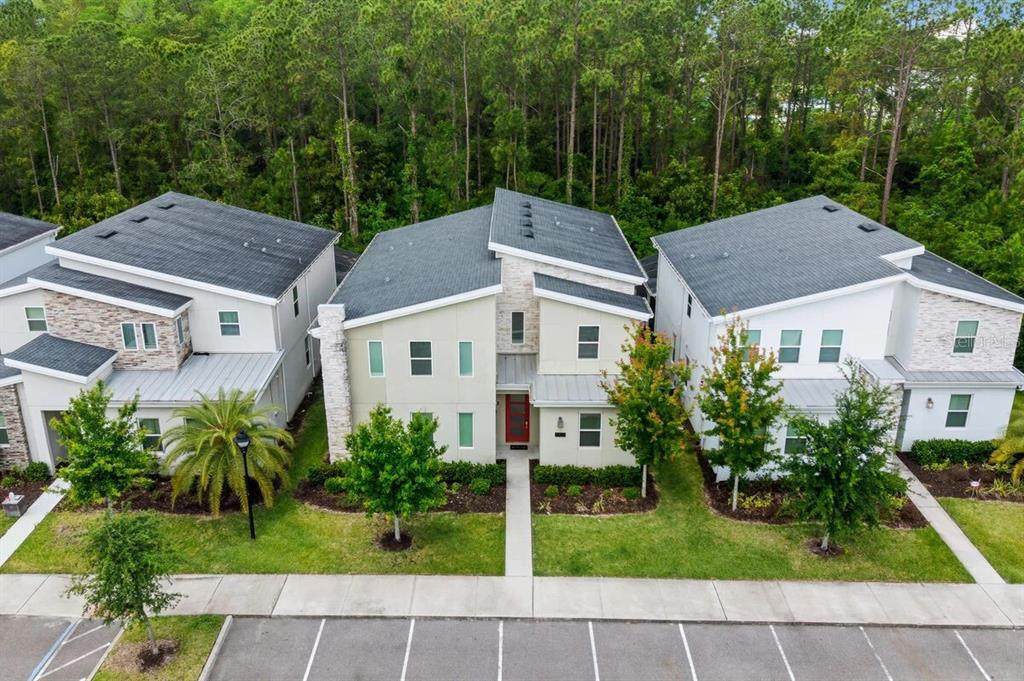 An aerial view shows three modern two-story houses with gray roofs and landscaped front yards — 2703 BOOKMARK DRIVE, KISSIMMEE, FL