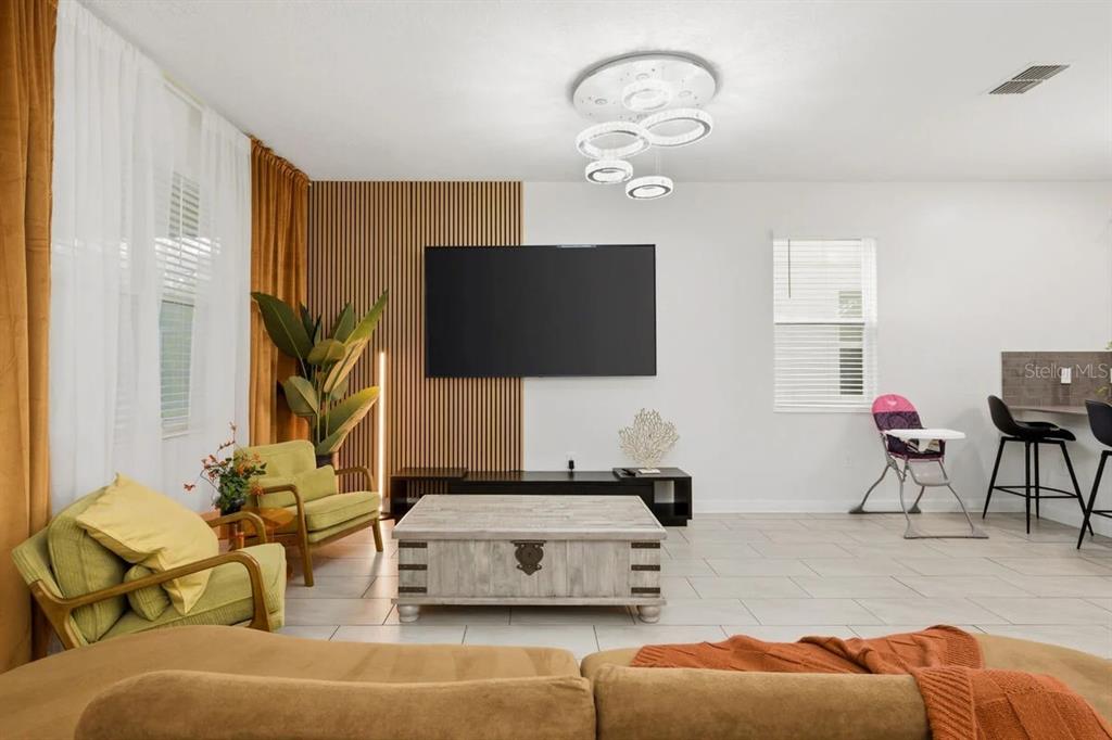 A living room features a slatted wood accent wall, a television, and a coffee table — 2703 BOOKMARK DRIVE, KISSIMMEE, FL