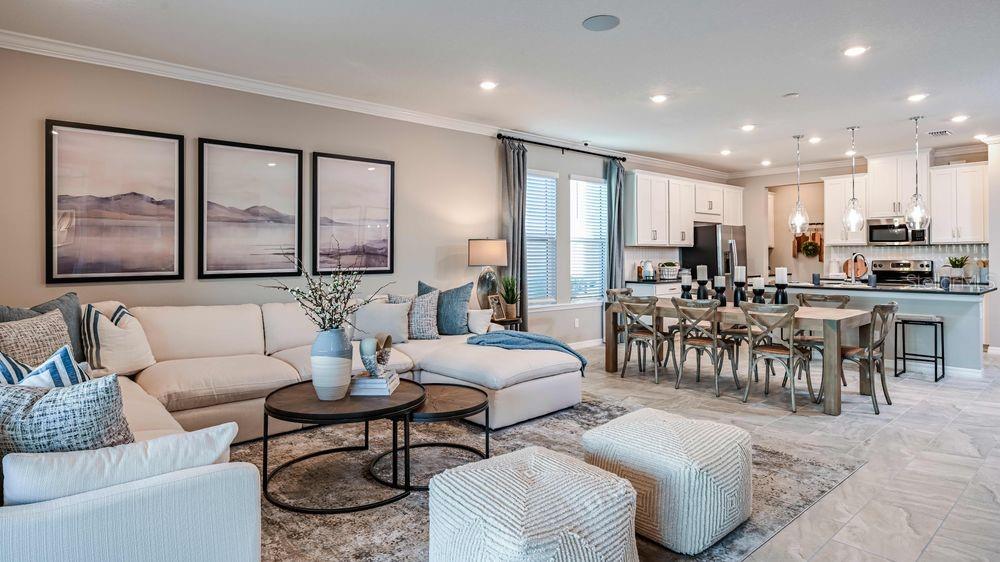 An open-concept living room and kitchen featuring a sectional sofa, dining table, and white cabinetry — 15532 FOXTAIL LANE, NOKOMIS, FL