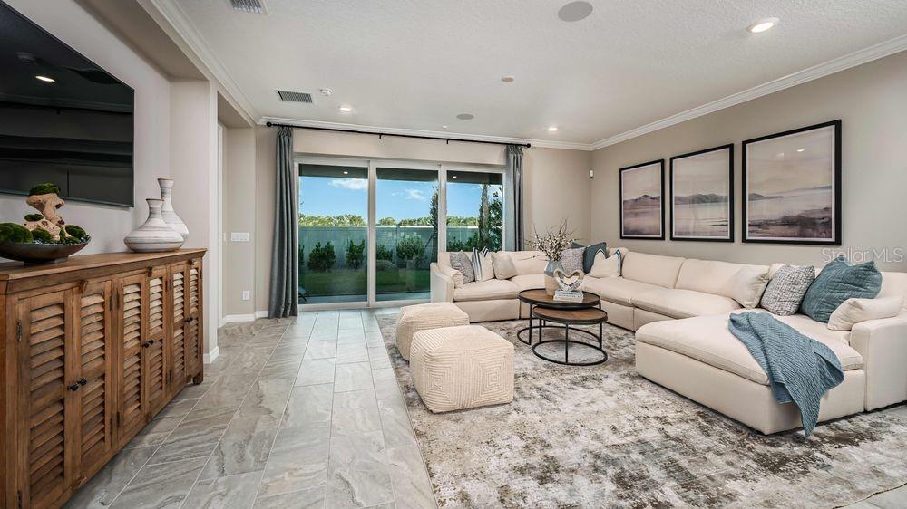 A living room features a large sectional sofa, a wooden console, and sliding glass doors — 15532 FOXTAIL LANE, NOKOMIS, FL