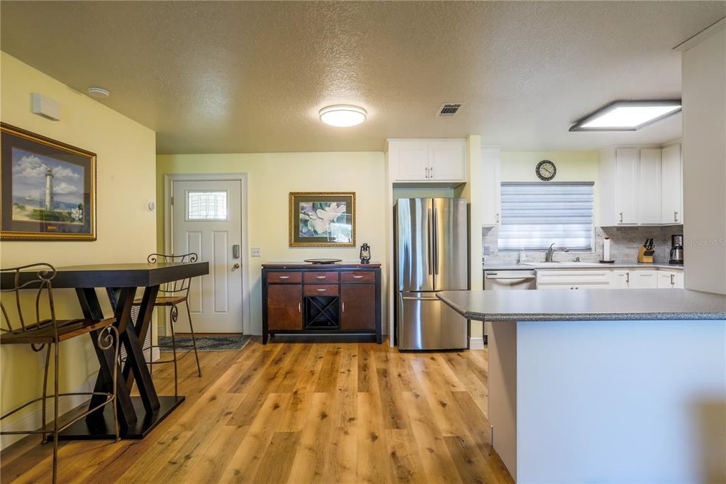 A kitchen and dining area feature wood-look flooring, stainless steel appliances, and a breakfast bar — 260 S CENTRAL AVENUE, UMATILLA, FL