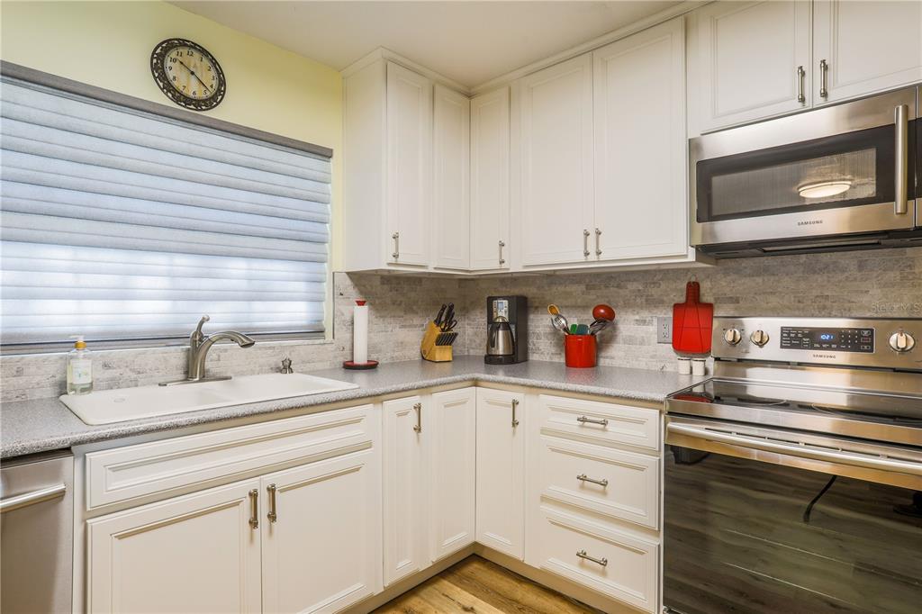 A kitchen features white cabinets, stainless steel appliances, a gray countertop, and a tiled backsplash — 260 S CENTRAL AVENUE, UMATILLA, FL
