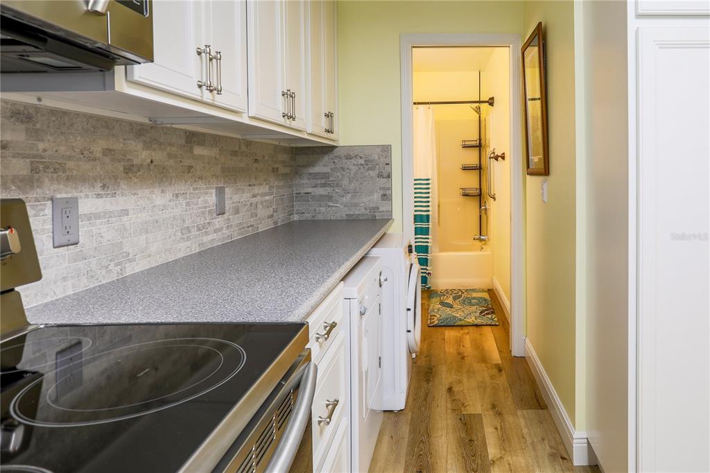 A kitchen with white cabinets, gray countertops, and a washer-dryer unit leading to a bathroom — 260 S CENTRAL AVENUE, UMATILLA, FL