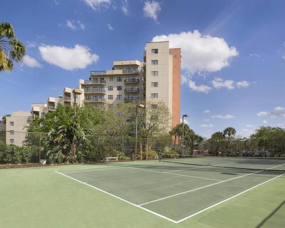 A tennis court sits in the foreground with a multi-story apartment building in the background — 6165 CARRIER DRIVE UNIT 2510, ORLANDO, FL