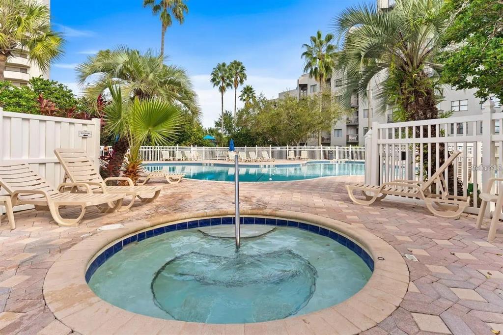 A circular hot tub sits on a brick patio in front of a swimming pool — 6165 CARRIER DRIVE UNIT 2510, ORLANDO, FL