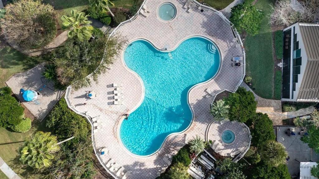 An aerial view shows a clover-shaped swimming pool with two attached hot tubs and deck — 6165 CARRIER DRIVE UNIT 2510, ORLANDO, FL