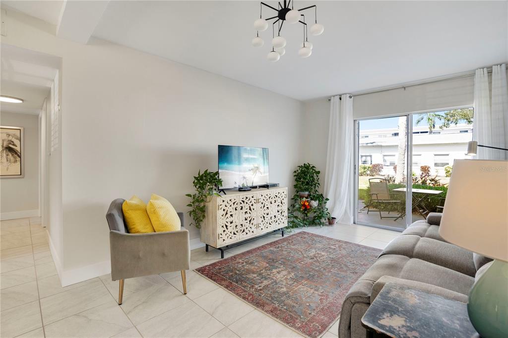 A living room features tile floors, a patterned area rug, and a sliding glass door — 2211 SUNSET DRIVE UNIT E3, BRADENTON, FL