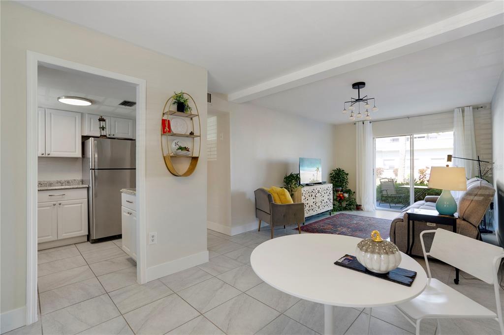 A bright living room and dining area with tile floors lead to a kitchen and patio — 2211 SUNSET DRIVE UNIT E3, BRADENTON, FL