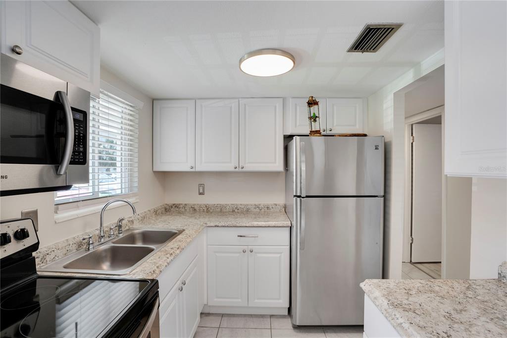 A kitchen features white cabinets, stainless steel appliances, and granite countertops — 2211 SUNSET DRIVE UNIT E3, BRADENTON, FL