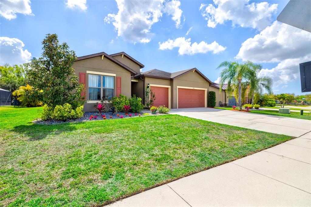 A single-story house with a brown exterior, two garage doors, and a front lawn — 11216 58TH STREET CIRCLE E, PARRISH, FL