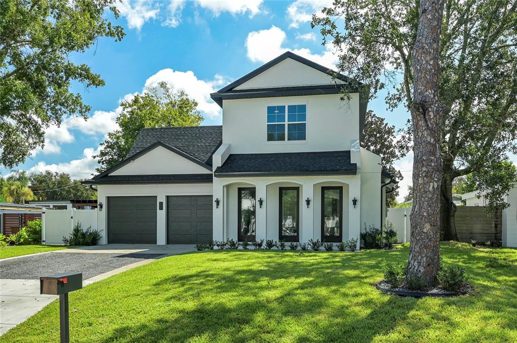 A two-story white house with a dark roof, two-car garage, and three front glass doors — 2430 CHANTILLY AVENUE, WINTER PARK, FL