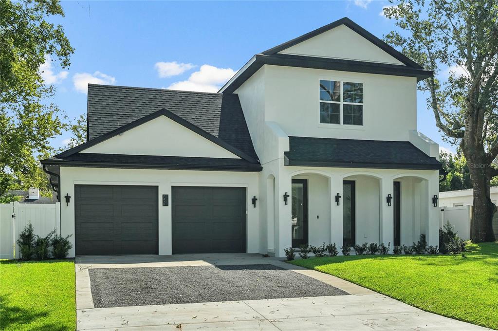 A two-story house with white stucco walls, a black roof, and a two-car garage — 2430 CHANTILLY AVENUE, WINTER PARK, FL