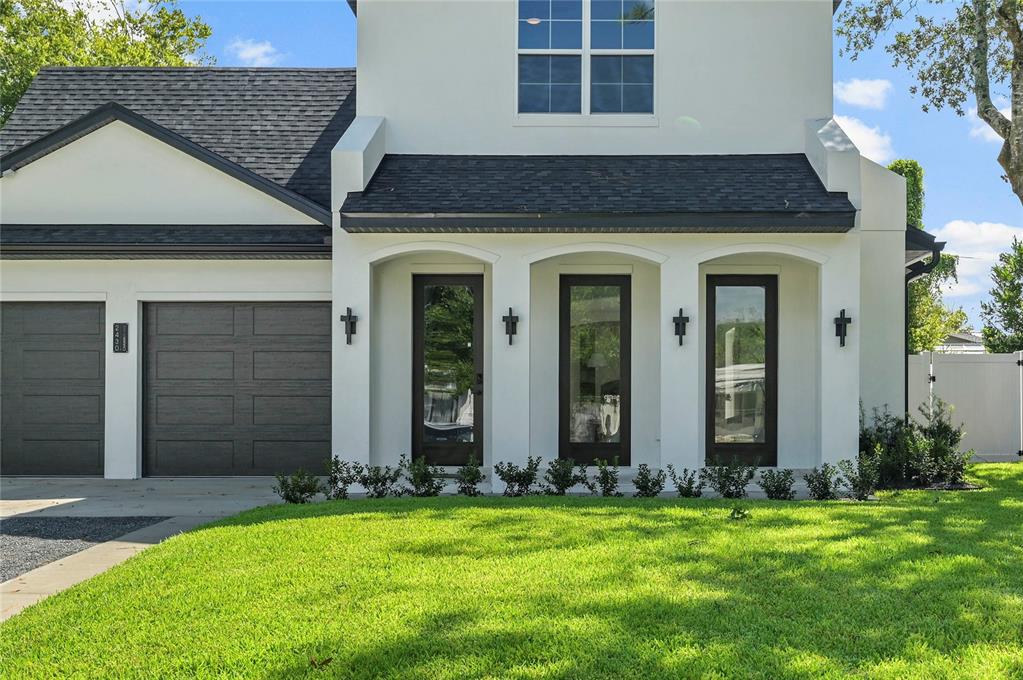 A white two-story house features a dark shingled roof, a garage, and three glass doors — 2430 CHANTILLY AVENUE, WINTER PARK, FL