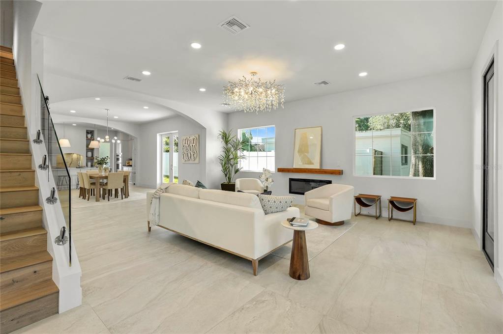 A bright, open-concept living room features a white sofa, modern fireplace, and a glass-railed staircase — 2430 CHANTILLY AVENUE, WINTER PARK, FL