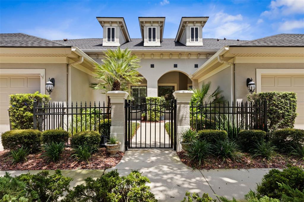 A gated courtyard entrance leads to a single-story home with three dormer windows above — 7 RIVER LANDING DRIVE, PALM COAST, FL