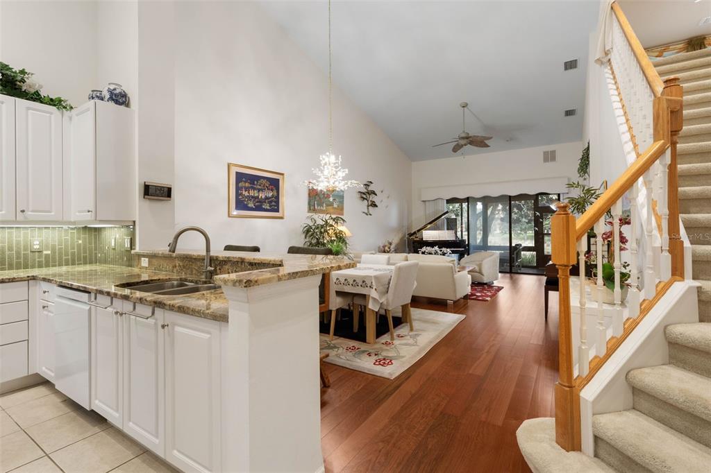 A kitchen with white cabinets and granite countertops overlooks a dining area and living room — 7 RIVER LANDING DRIVE, PALM COAST, FL