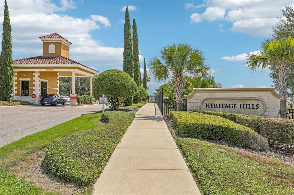 A sidewalk leads toward a gated community entrance with a guardhouse and stone signage — 2823 MAYPORT STREET, CLERMONT, FL