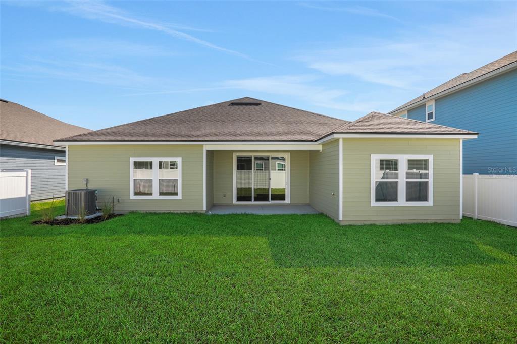 The exterior rear view of a light green house with a lawn and patio — 2254 BRANNINGS SAWMILL COURT, MIDDLEBURG, FL