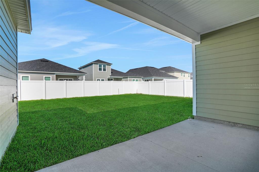 A concrete patio overlooks a grassy backyard enclosed by a white vinyl privacy fence — 2254 BRANNINGS SAWMILL COURT, MIDDLEBURG, FL
