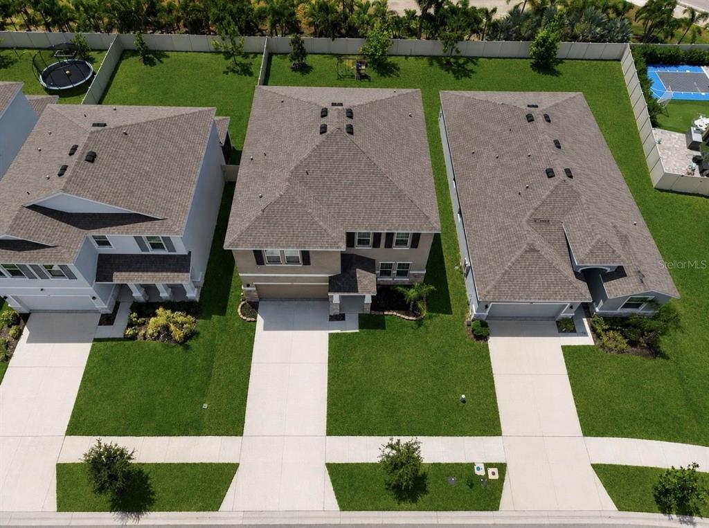 An aerial view shows three suburban houses with driveways and backyards in a residential neighborhood — 172 MANGROVE MANOR DRIVE, APOLLO BEACH, FL