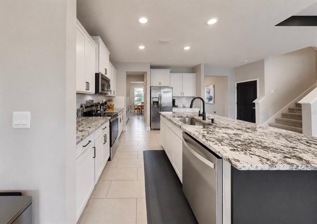 A modern kitchen features white cabinets, granite countertops, stainless steel appliances, and a central island — 172 MANGROVE MANOR DRIVE, APOLLO BEACH, FL