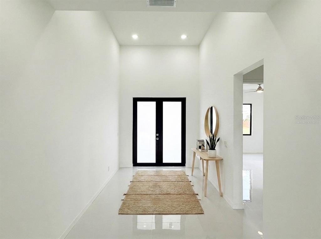 A bright entryway features white walls, tile flooring, a jute rug, and black double doors — 4005 NW 22ND STREET, CAPE CORAL, FL