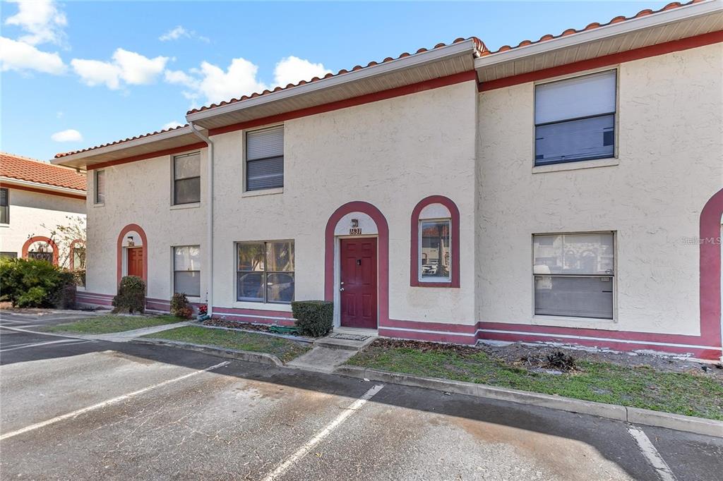A two-story townhouse exterior features red doors, arched entryways, and a terracotta tile roof — 1631 LITTLE FALLS CIRCLE UNIT 92, ORLANDO, FL