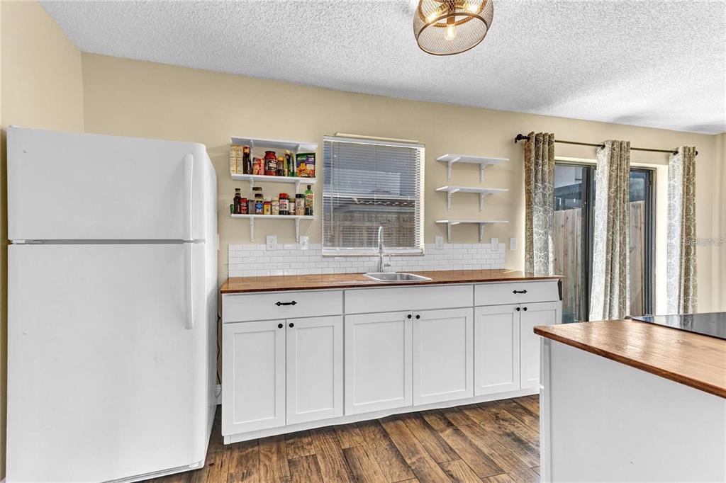 A kitchen features white cabinets, a wood countertop, open shelving, and a white refrigerator — 1631 LITTLE FALLS CIRCLE UNIT 92, ORLANDO, FL