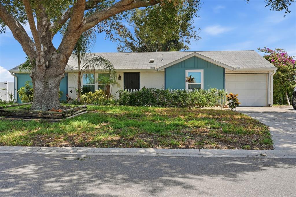 A single-story house with a teal facade, a white garage door, and a large front tree — 3403 68TH STREET W, BRADENTON, FL