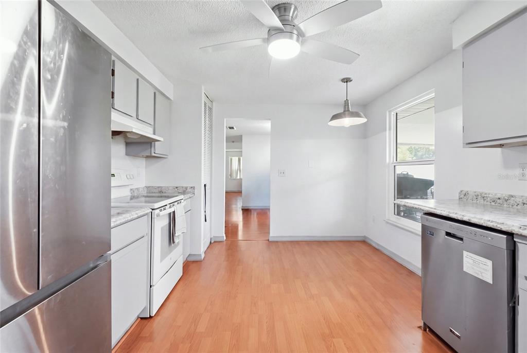 A kitchen with stainless steel appliances, white cabinets, granite countertops, and light wood flooring — 3403 68TH STREET W, BRADENTON, FL