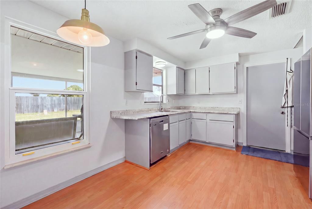 A kitchen features light gray cabinets, a stainless steel dishwasher, and wood-look flooring — 3403 68TH STREET W, BRADENTON, FL