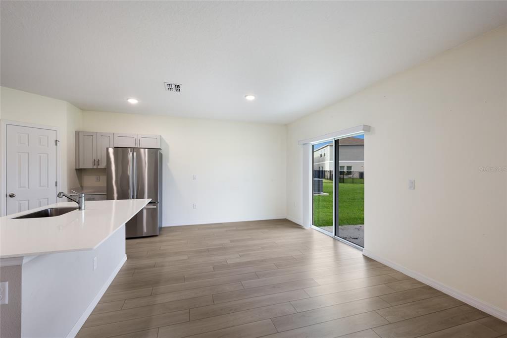 A kitchen with a white island, stainless steel refrigerator, and sliding glass doors to a yard — 7627 TWINLEAF TERRACE, PARRISH, FL