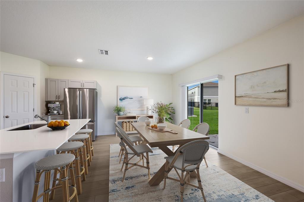 A kitchen with a center island and a dining area featuring a wooden table — 7627 TWINLEAF TERRACE, PARRISH, FL