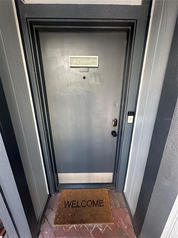 A gray front door with a welcome mat sits in a recessed entryway — 3793 ATRIUM DRIVE UNIT L6, ORLANDO, FL