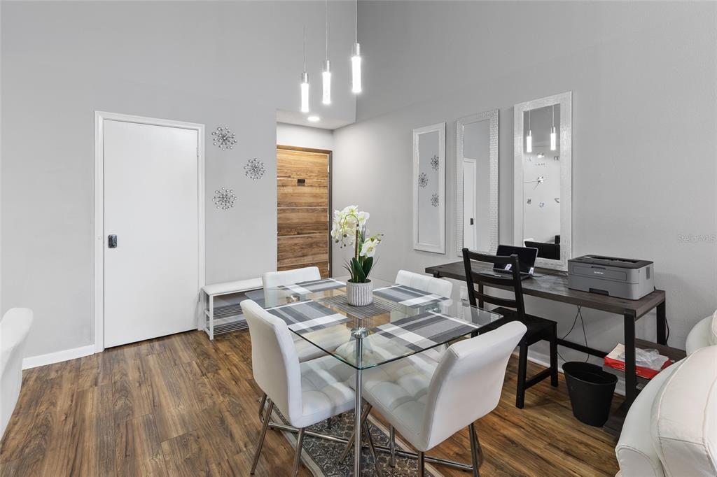 A dining area features a glass table, white chairs, a desk, and wood-look flooring — 3793 ATRIUM DRIVE UNIT L6, ORLANDO, FL