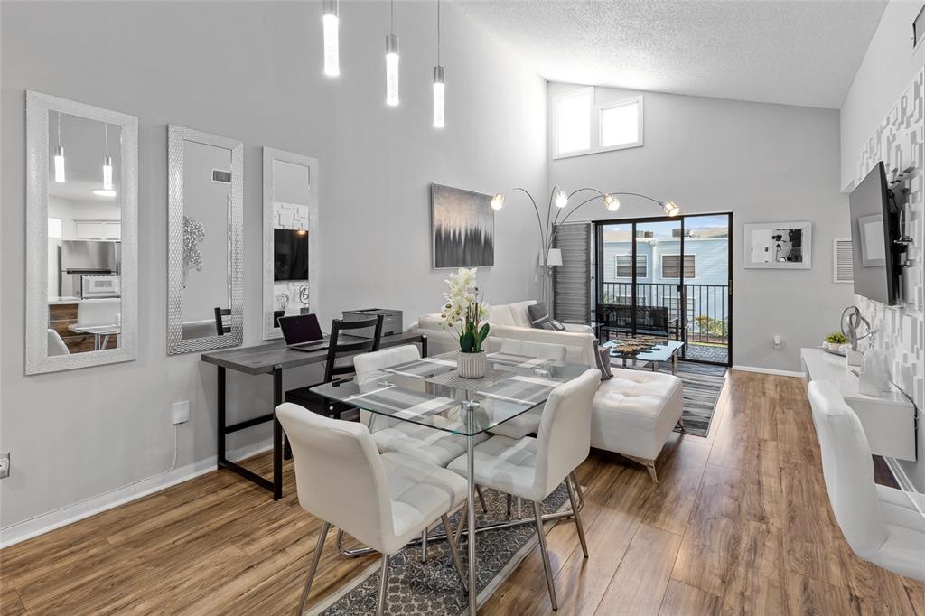 A living and dining area features wood-look flooring, a glass table, and a balcony view — 3793 ATRIUM DRIVE UNIT L6, ORLANDO, FL