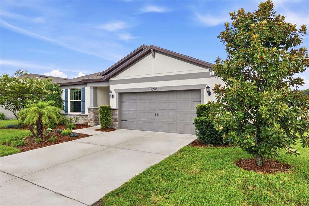 A single-story house with a gray garage, stone accents, and a landscaped front yard — 18515 CORTES CREEK BOULEVARD, SPRING HILL, FL