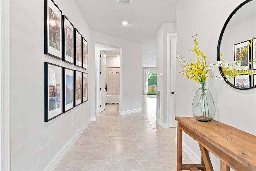 A hallway with tiled floors, a wooden console table, framed wall art, and a round mirror — 18515 CORTES CREEK BOULEVARD, SPRING HILL, FL